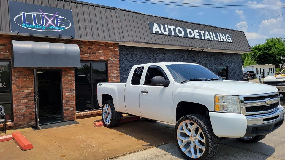 White pickup truck parked in front of Luxe Auto Detailing shop.