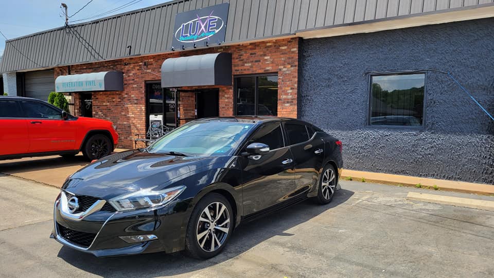 Black Nissan Maxima parked outside a business, 
