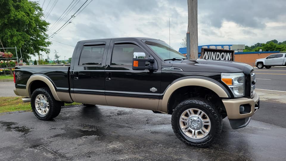 Black and tan Ford F-350 truck parked on wet pavement.