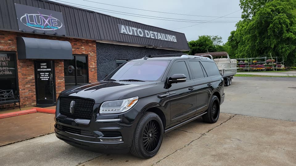 Black Lincoln Navigator parked outside a car detailing business.