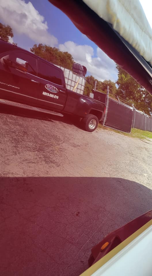 Red truck parked in a gravel lot, reflecting in a shiny, red surface; blue sky above.