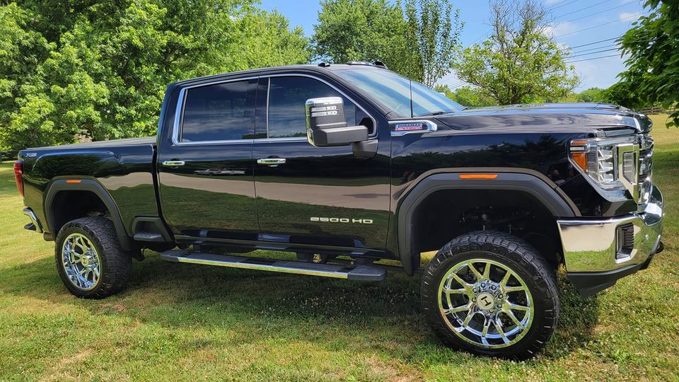 Black GMC Sierra HD pickup truck parked on grass.