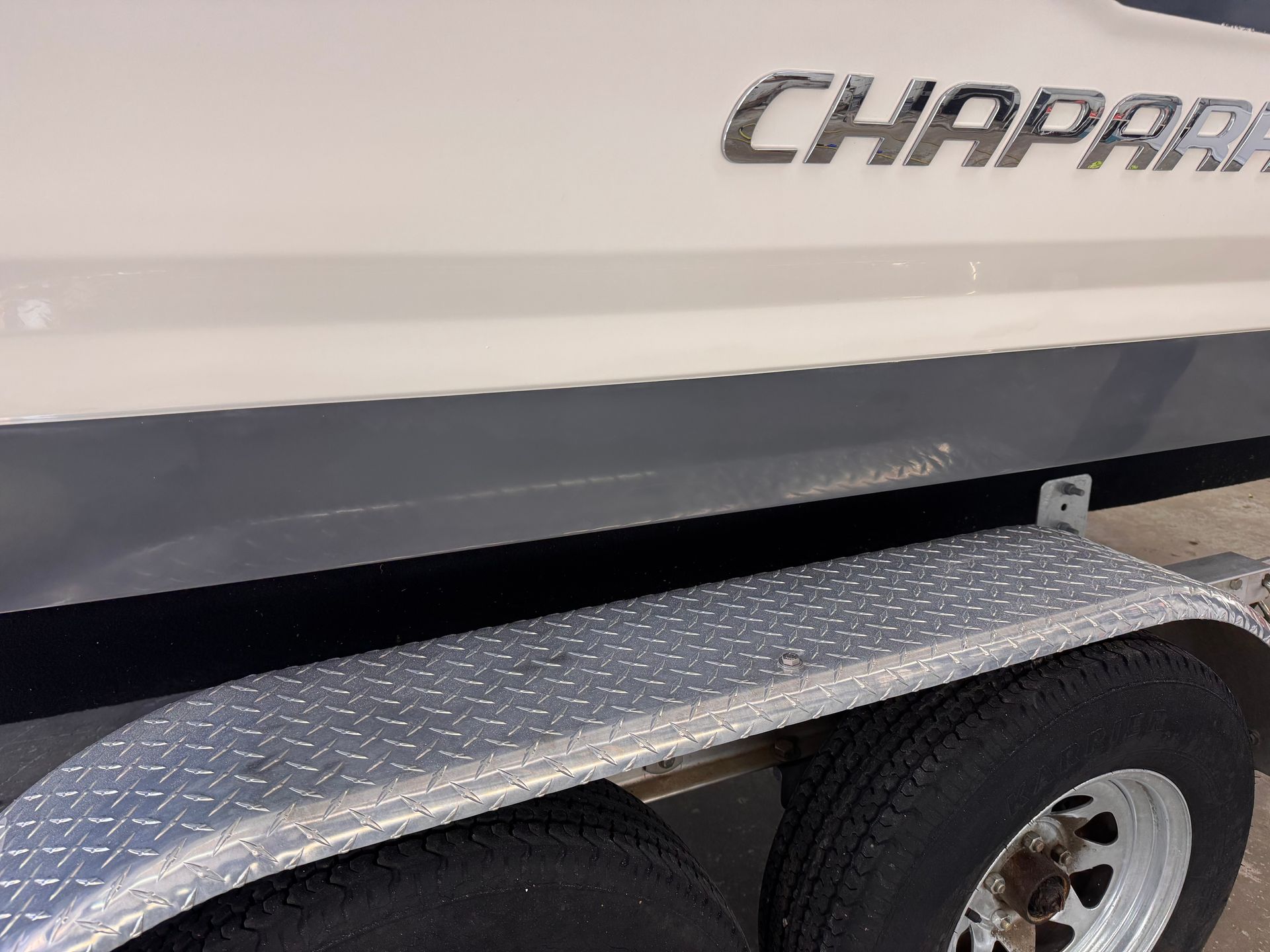 Gray and white Chaparral boat, parked on a trailer with diamond-plate fenders.