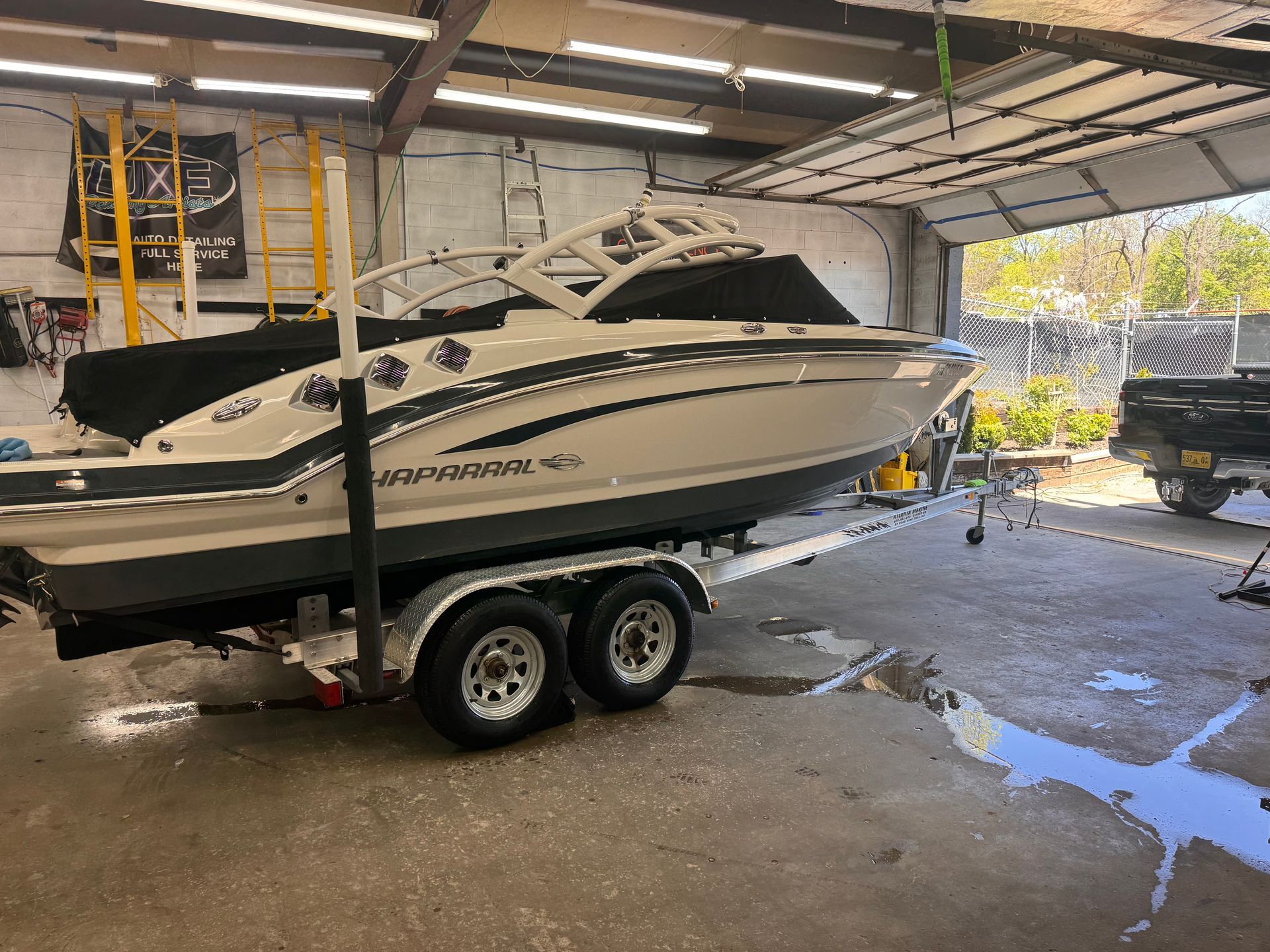Boat on a trailer inside a garage. White and black hull with chrome accents.