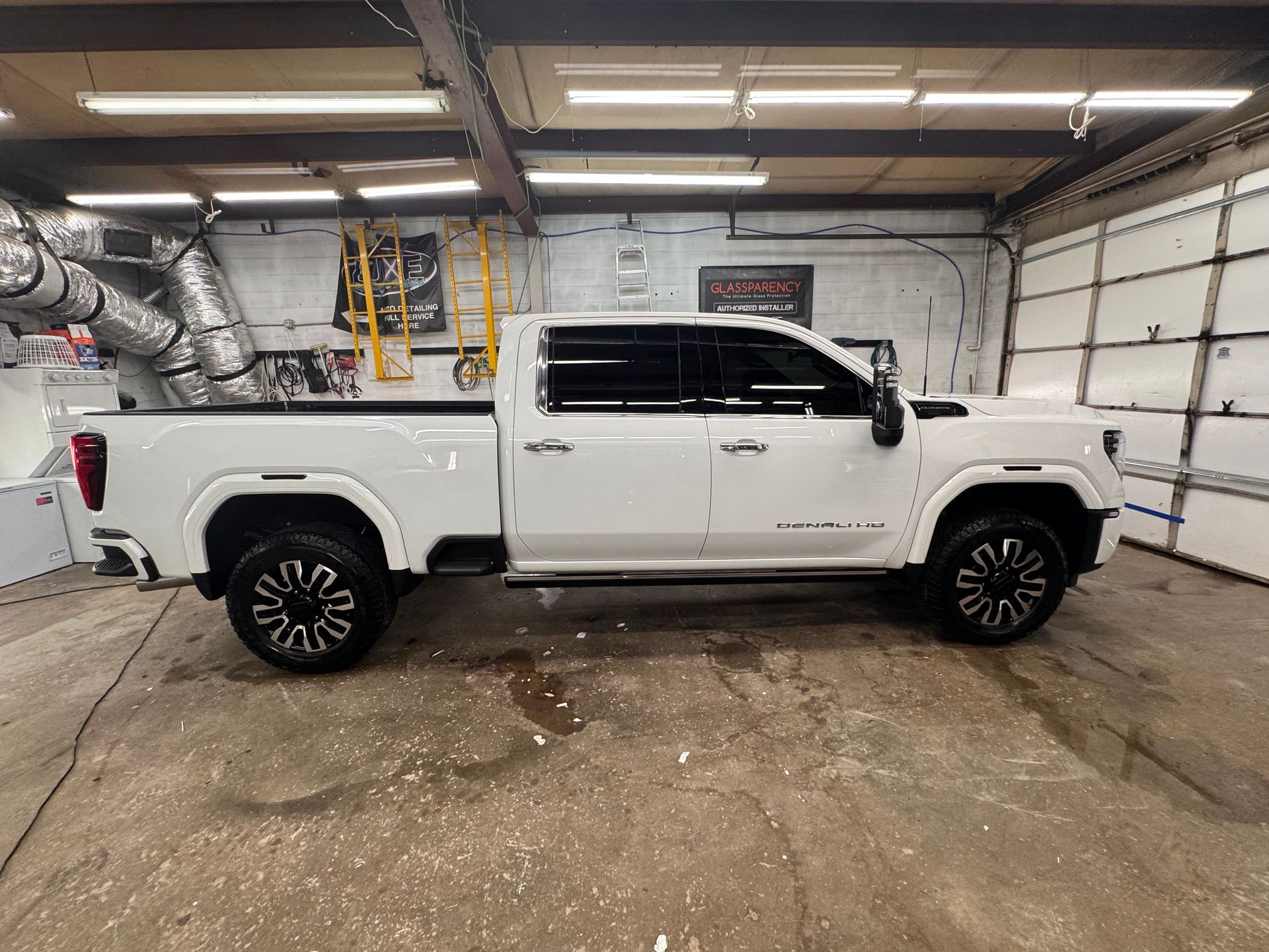White GMC truck with black wheels inside a garage.