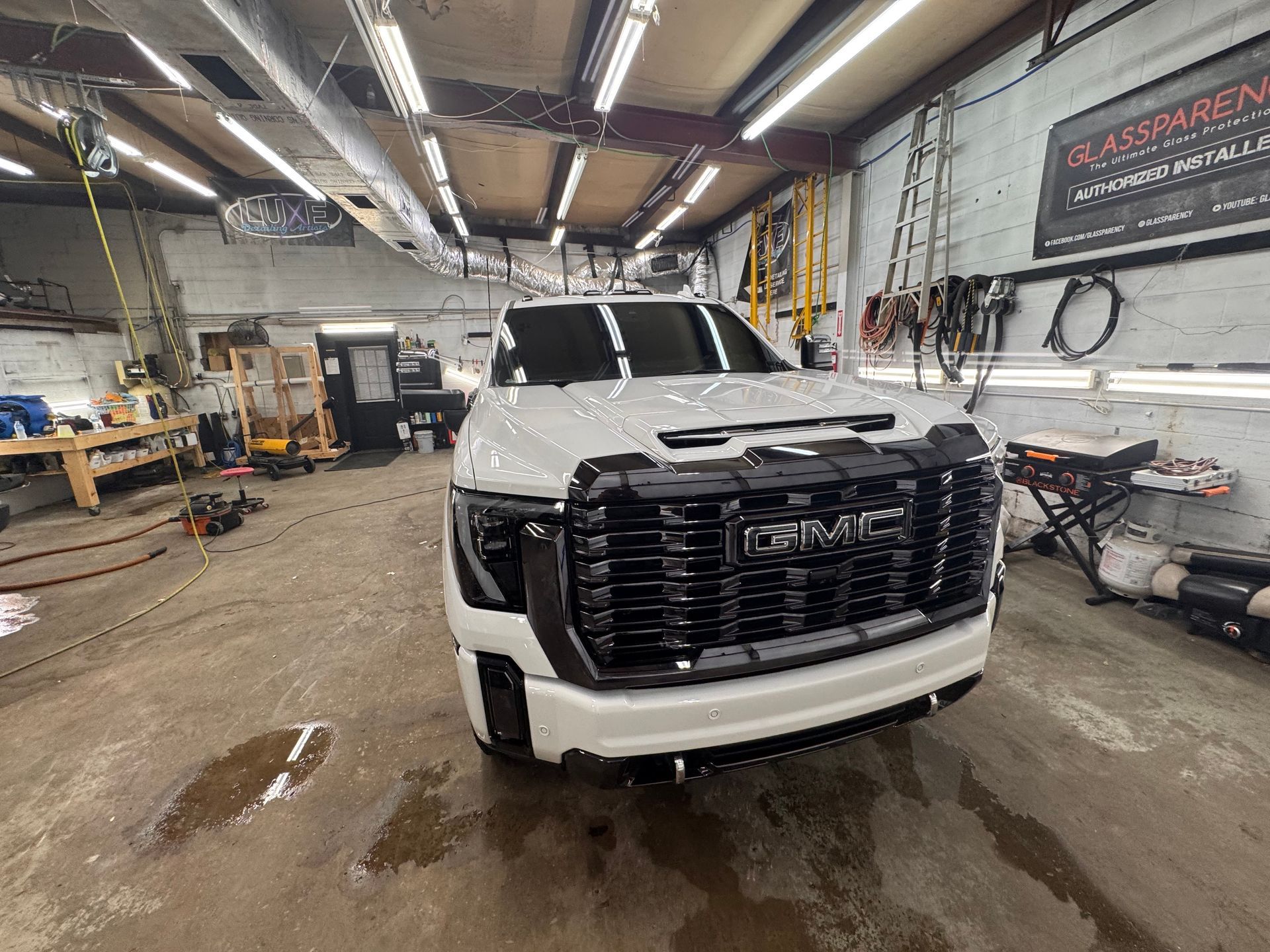 White GMC truck in a garage, with black grille, front and center.