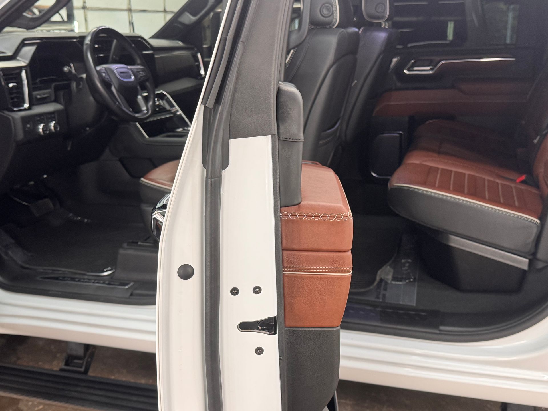 Open white truck door revealing interior with brown and black leather seats.