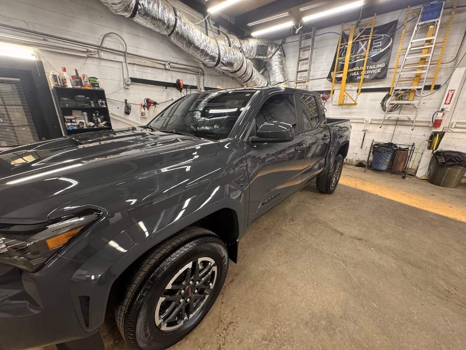 Gray pickup truck being detailed inside a garage.
