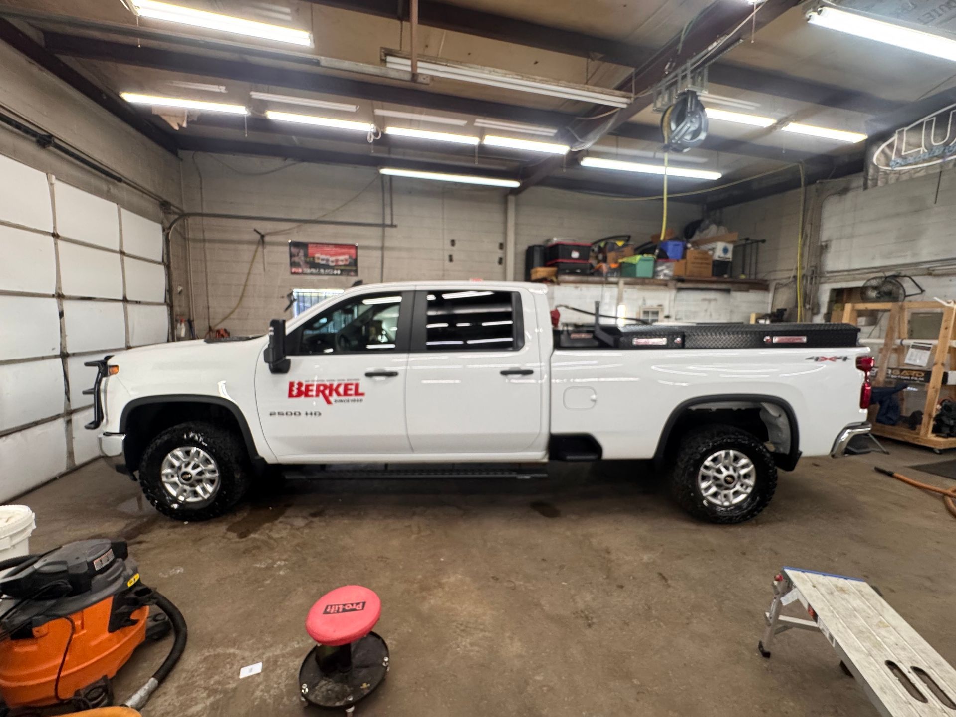 White pickup truck with company logo inside a garage.