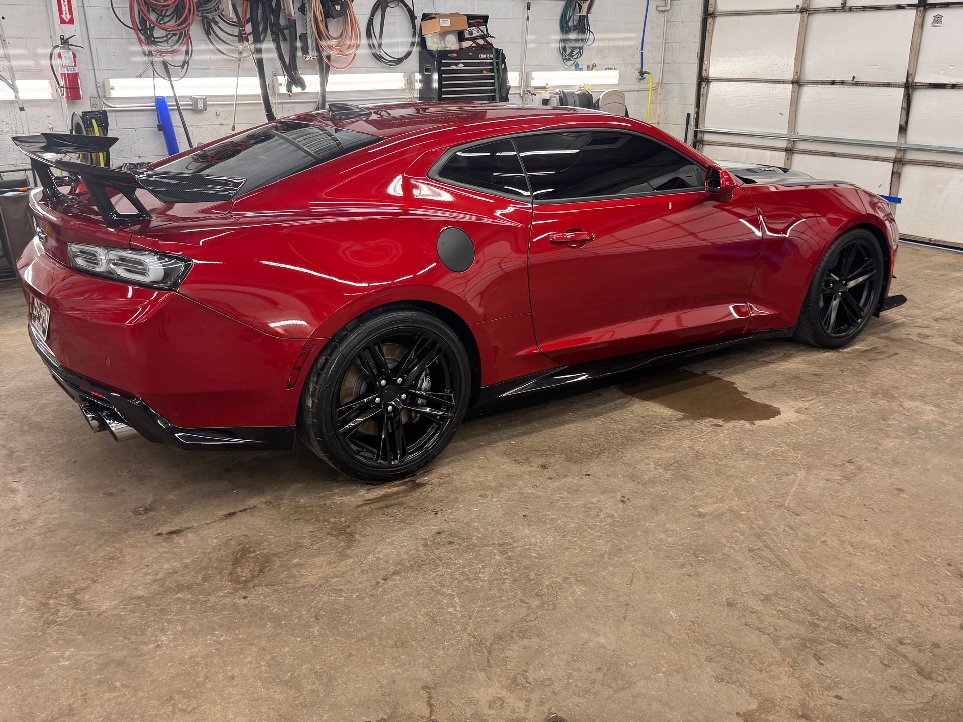 Red sports car in a garage; black wheels and trim.