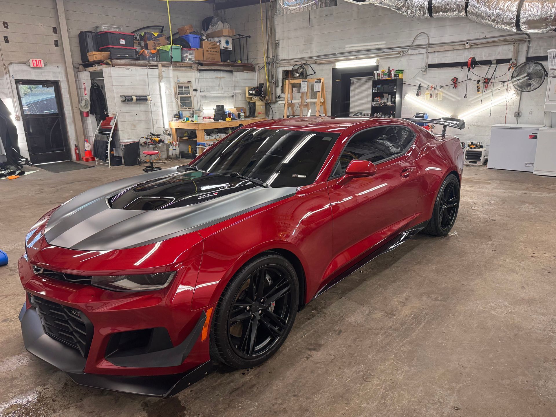 Red Chevrolet Camaro with black accents in a garage.
