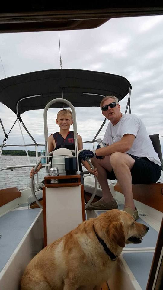 A man and a boy are sitting on a boat with a dog.