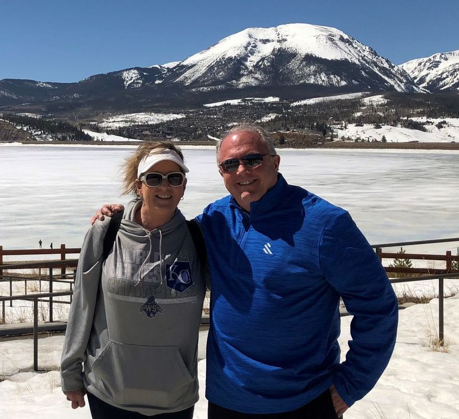 A man and a woman are posing for a picture in front of a snowy mountain