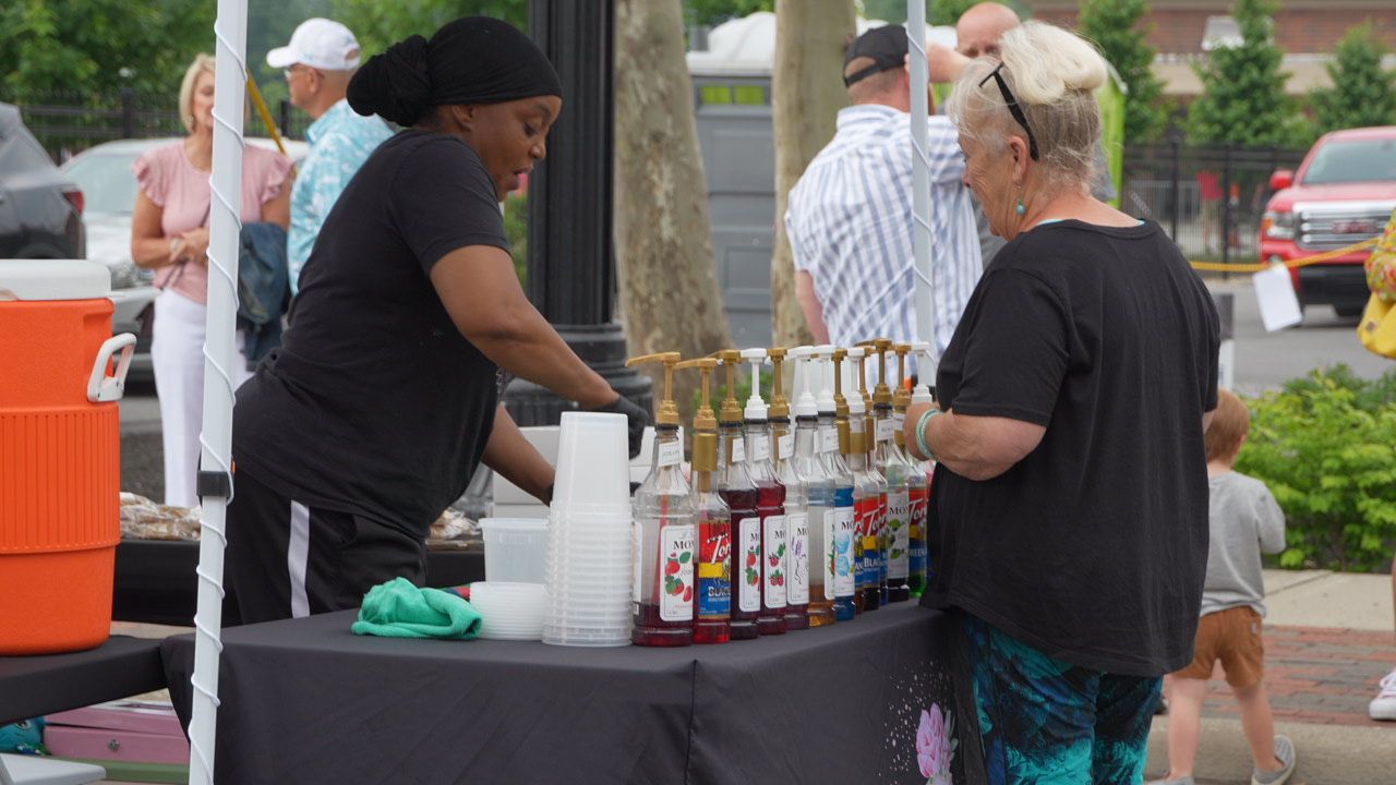 Three people on a carnival ride: blue car, red and orange shirts, big smiles, other rides and people in the background.