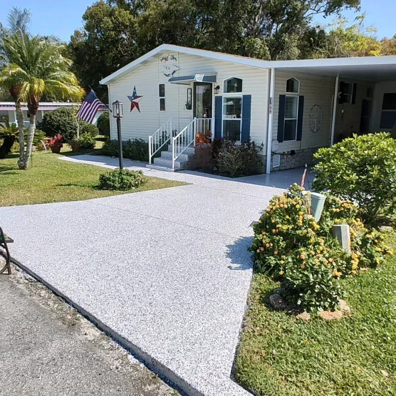 Mobile home with paved driveway and landscaping, American flag.