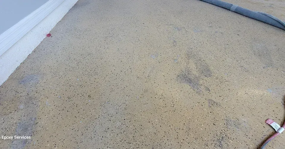 Tan carpet with dark spots and faint gray footprints.