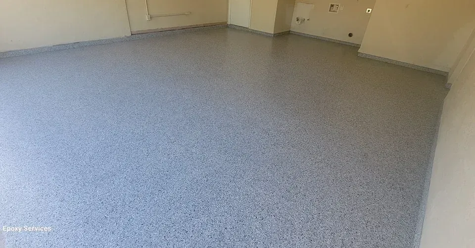 Gray speckled epoxy floor in a room with beige walls and a low baseboard.