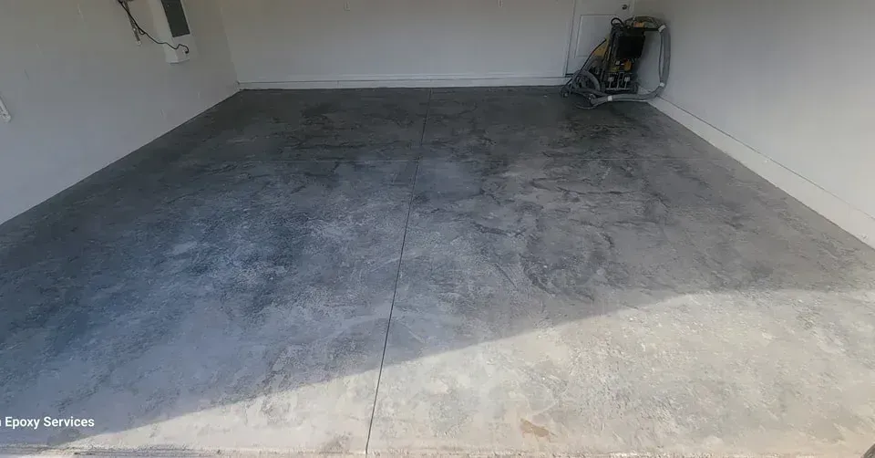 Concrete garage floor with visible cracks and appliance in corner.