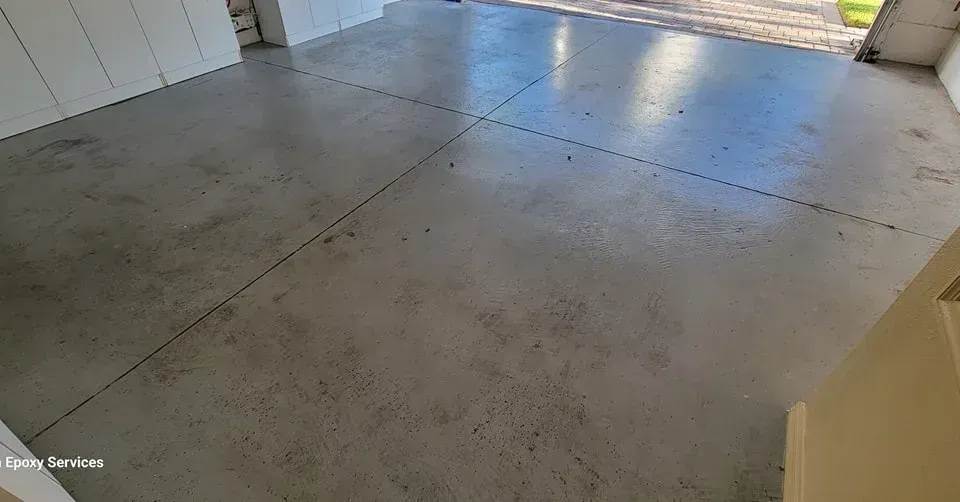 Gray concrete floor, possibly a garage or driveway, with visible expansion joints and some debris.