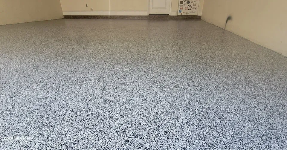 Garage floor with a speckled, epoxy coating in shades of gray.