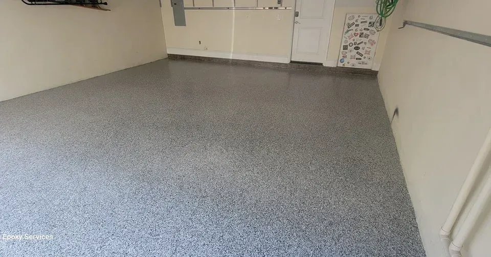 Gray speckled epoxy floor in a garage with off-white walls.