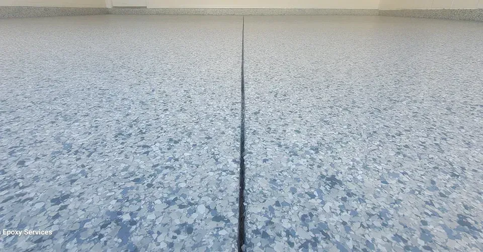 Close-up view of a floor with a long, dark crack running down the middle; flecked, light blue pattern.