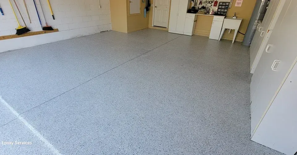 Garage with gray epoxy floor, white cabinets, and tools.