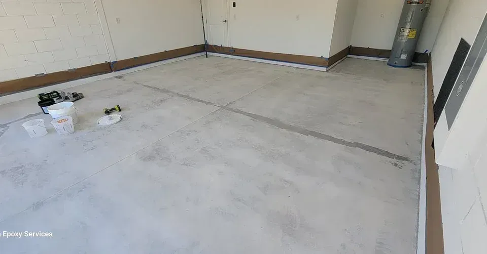 Garage with newly coated light gray concrete floor, some tools, and water heater.