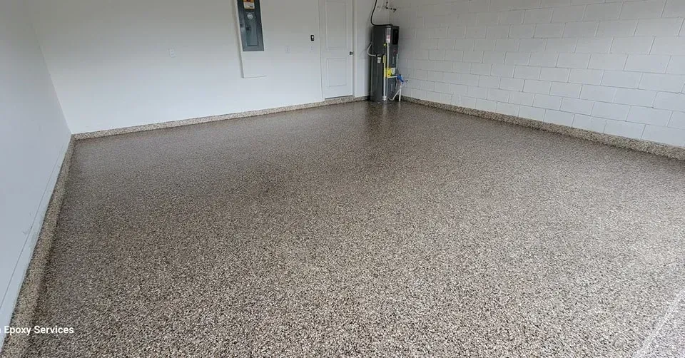 Epoxy-coated garage floor with various-colored chips. White walls, electrical panel, and water heater visible.