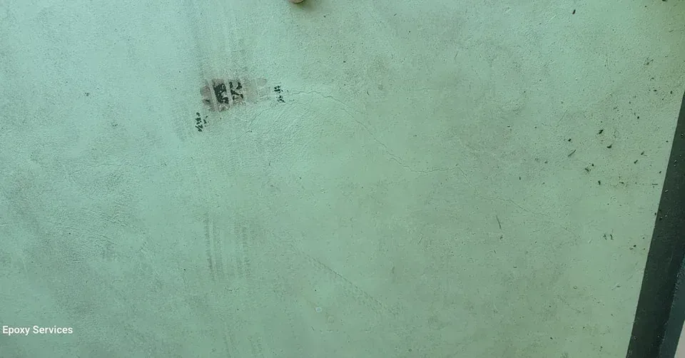 Light green painted wall with dark spots and a slightly angled dark edge.