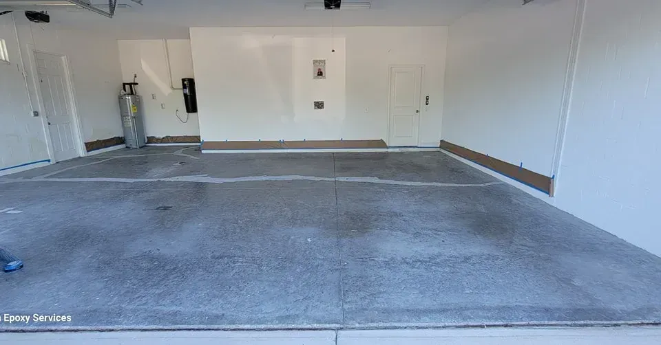 Empty garage with a gray concrete floor and white walls. A propane tank is in the corner.