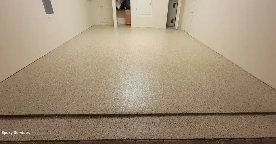 A room with a polished speckled floor; white walls; doorway at the back.