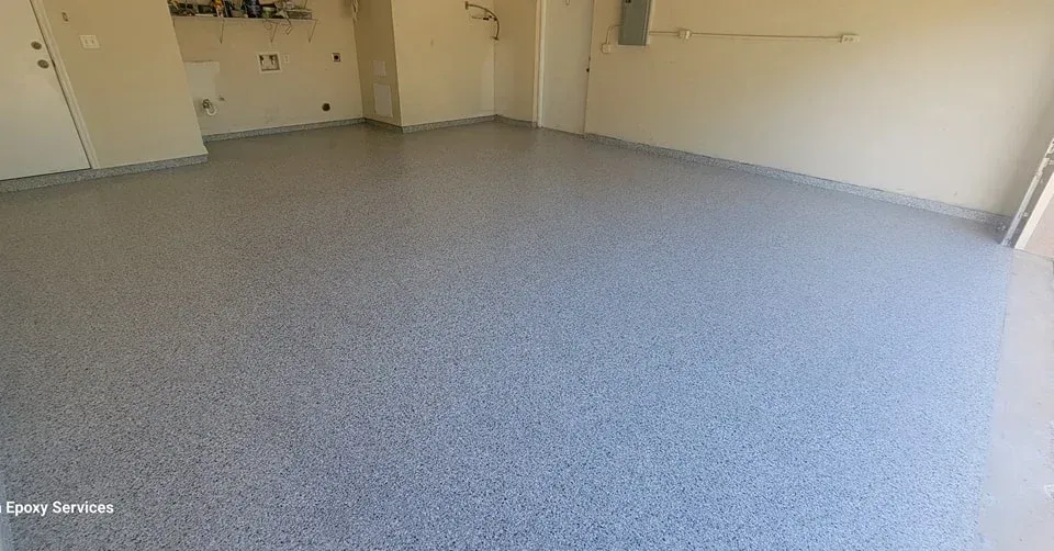 Empty garage with a gray, speckled epoxy floor.