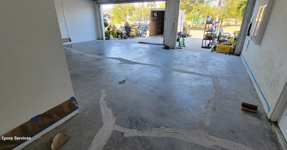 Concrete floor with white sealant, construction equipment in a garage-like space.