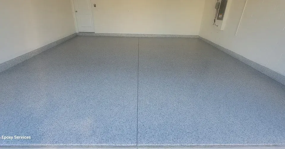 Empty garage with speckled gray epoxy floor and white walls.