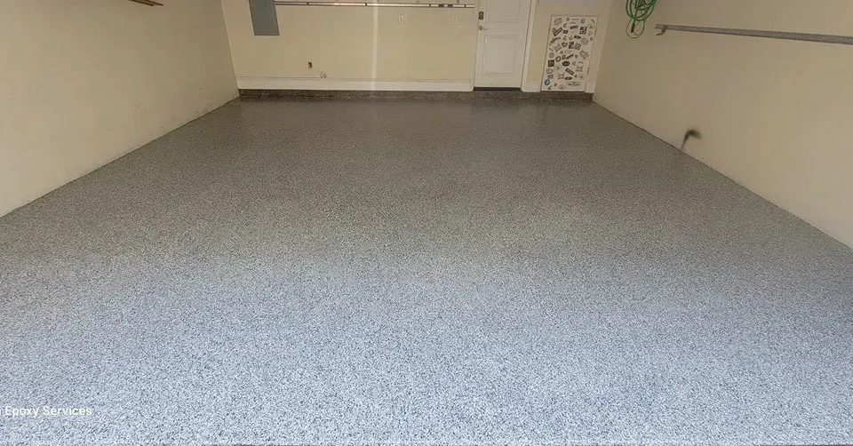 Grey speckled epoxy garage floor. Beige walls, utility sink, and white door are visible.