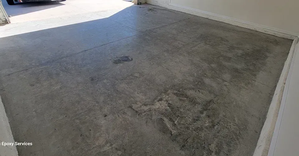Concrete garage floor with stains and sunlight.