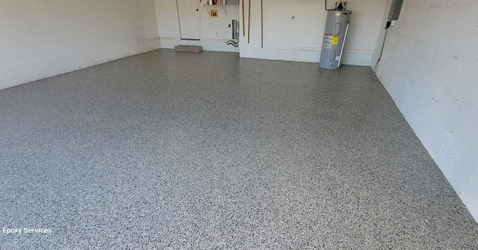 Garage with a speckled epoxy floor. White walls, water heater, and a door are visible.