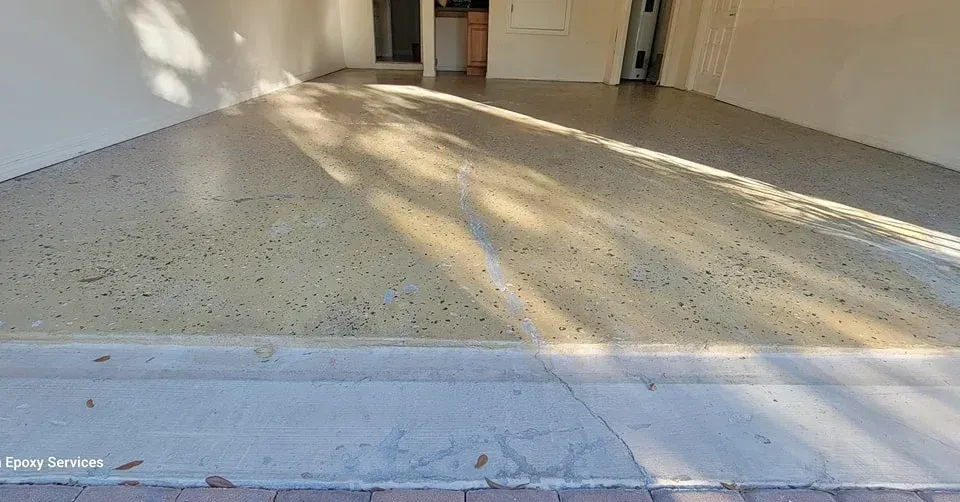 Garage with a speckled, light-colored concrete floor, lit by sunlight.