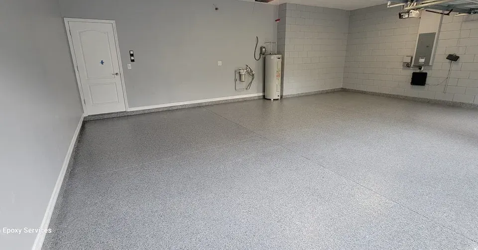 Empty, gray-floored garage with gray walls, white door, and water heater.