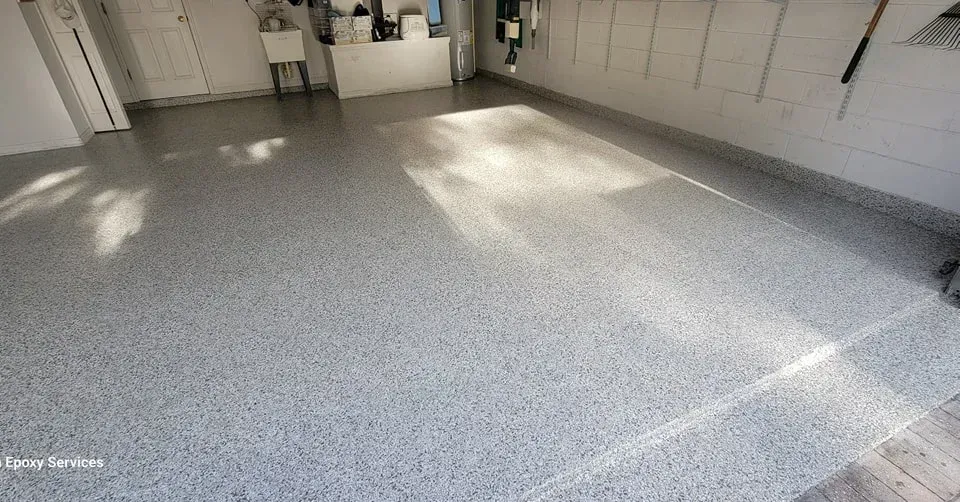 Gray speckled epoxy garage floor. Sunlit, clean, and empty.