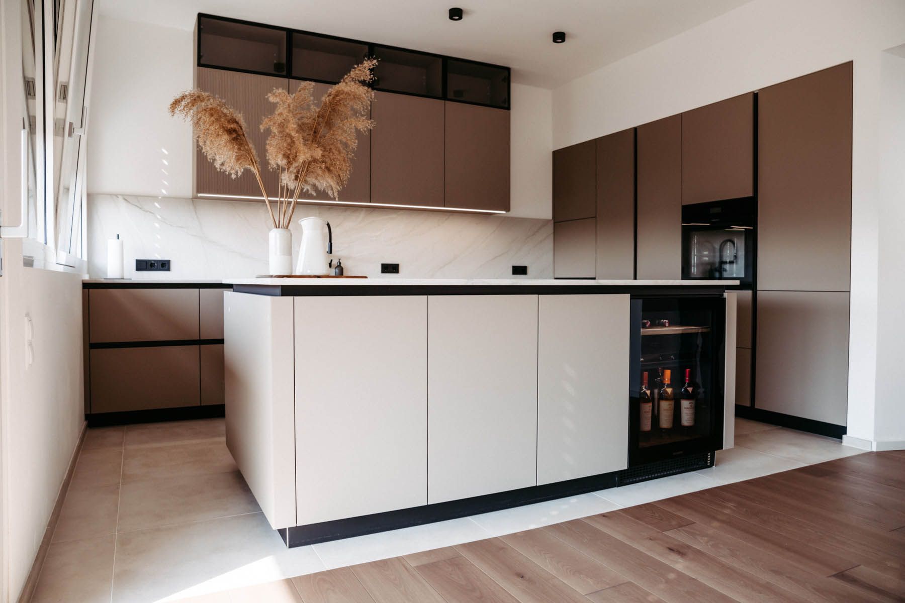 Moderne Küche mit braunen und beigen Schränken, Kochinsel mit Weinkühler und Holzböden.
