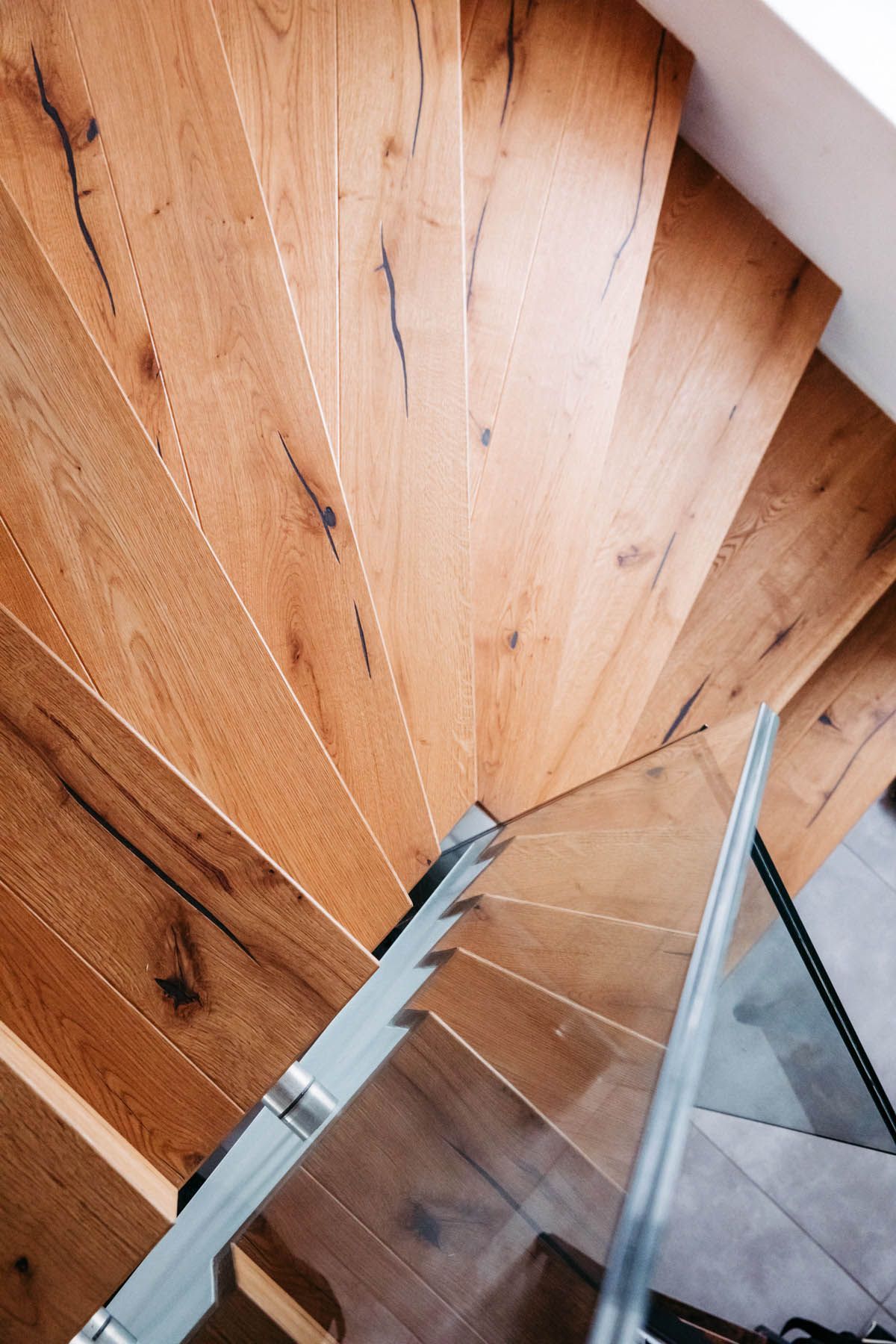 Wendeltreppe aus Holz mit Glasgeländer.