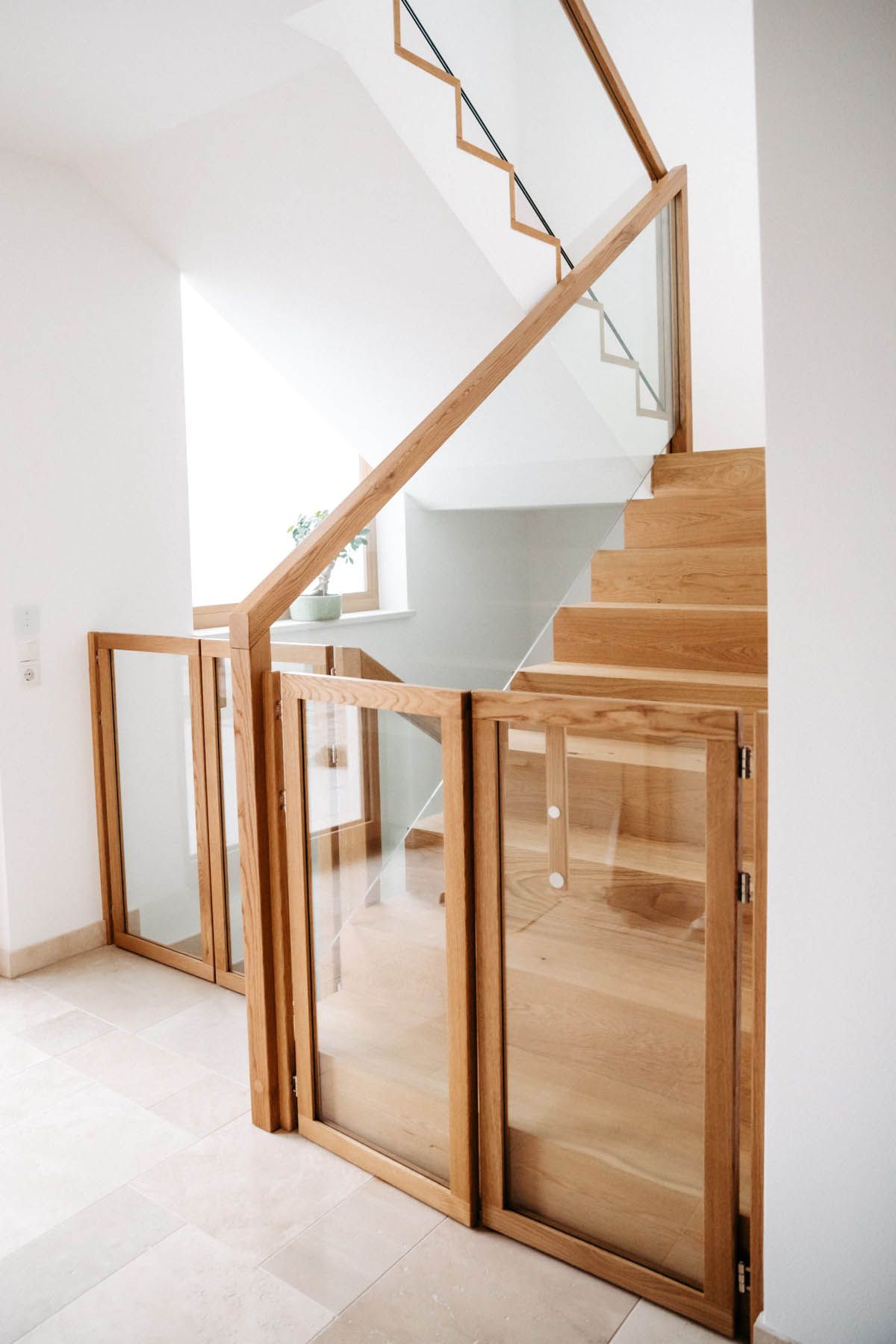 Holztreppe mit Glaspaneelen; unten ein Tor zur Sicherheit.