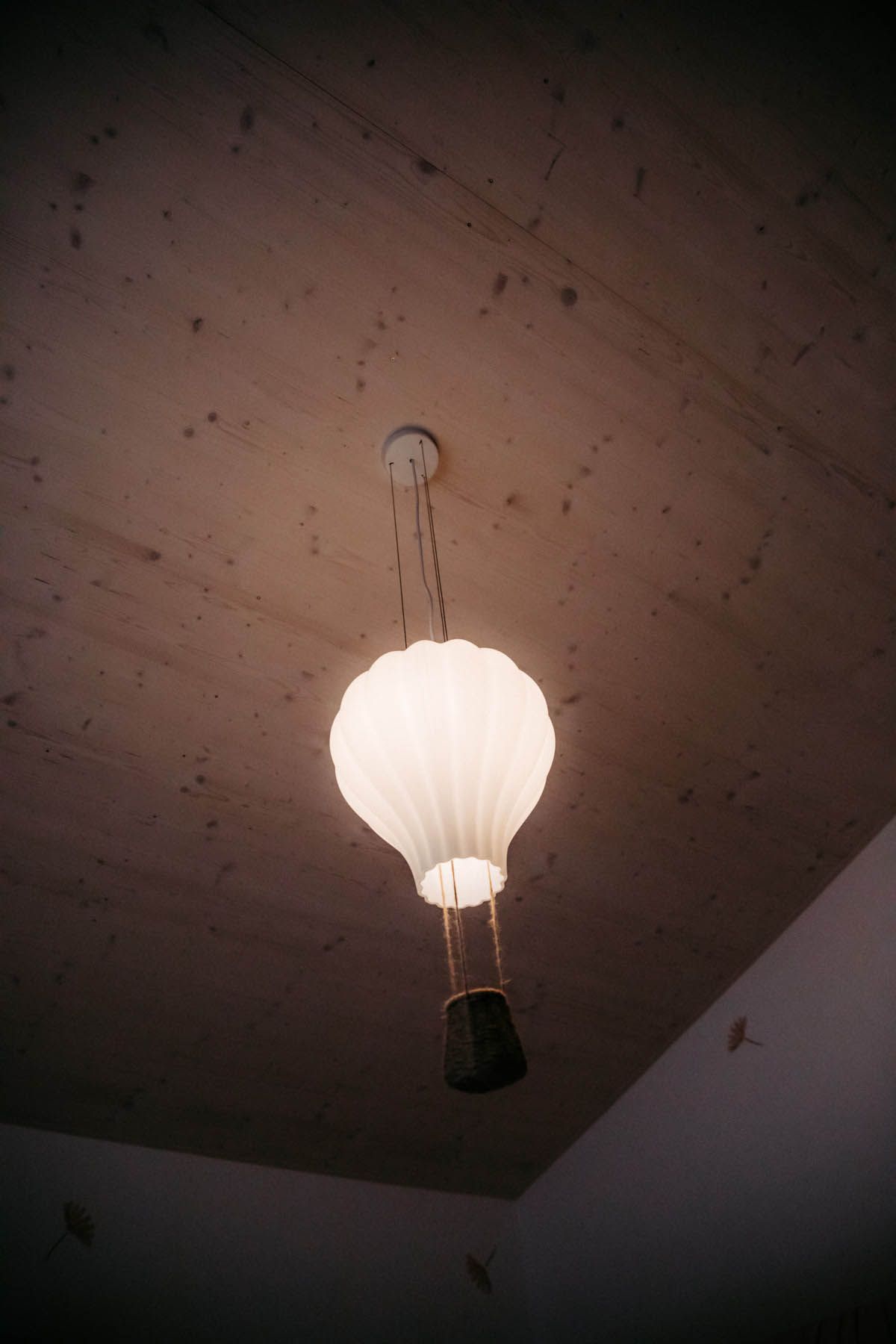 Eine skurrile Leuchte in Form eines Heißluftballons hängt von einer strukturierten Decke.