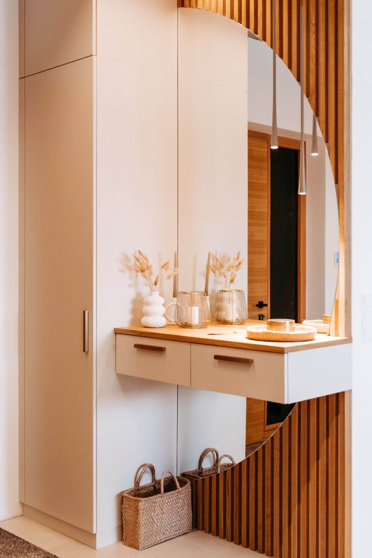 Beiger Eingangsbereich mit einem Schrank, einem schwebenden Konsolentisch und einem runden Spiegel.