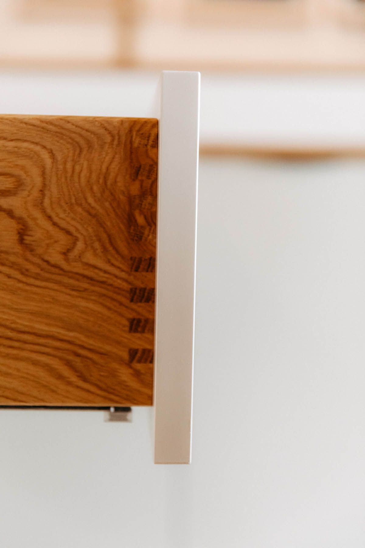 Nahaufnahme einer Holzschublade mit Schwalbenschwanzverbindungen, weißer Kante und hellem Hintergrund.