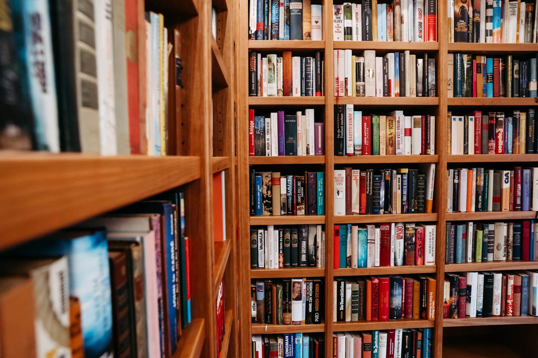 Holzbücherregale voller Bücher in verschiedenen Farben.