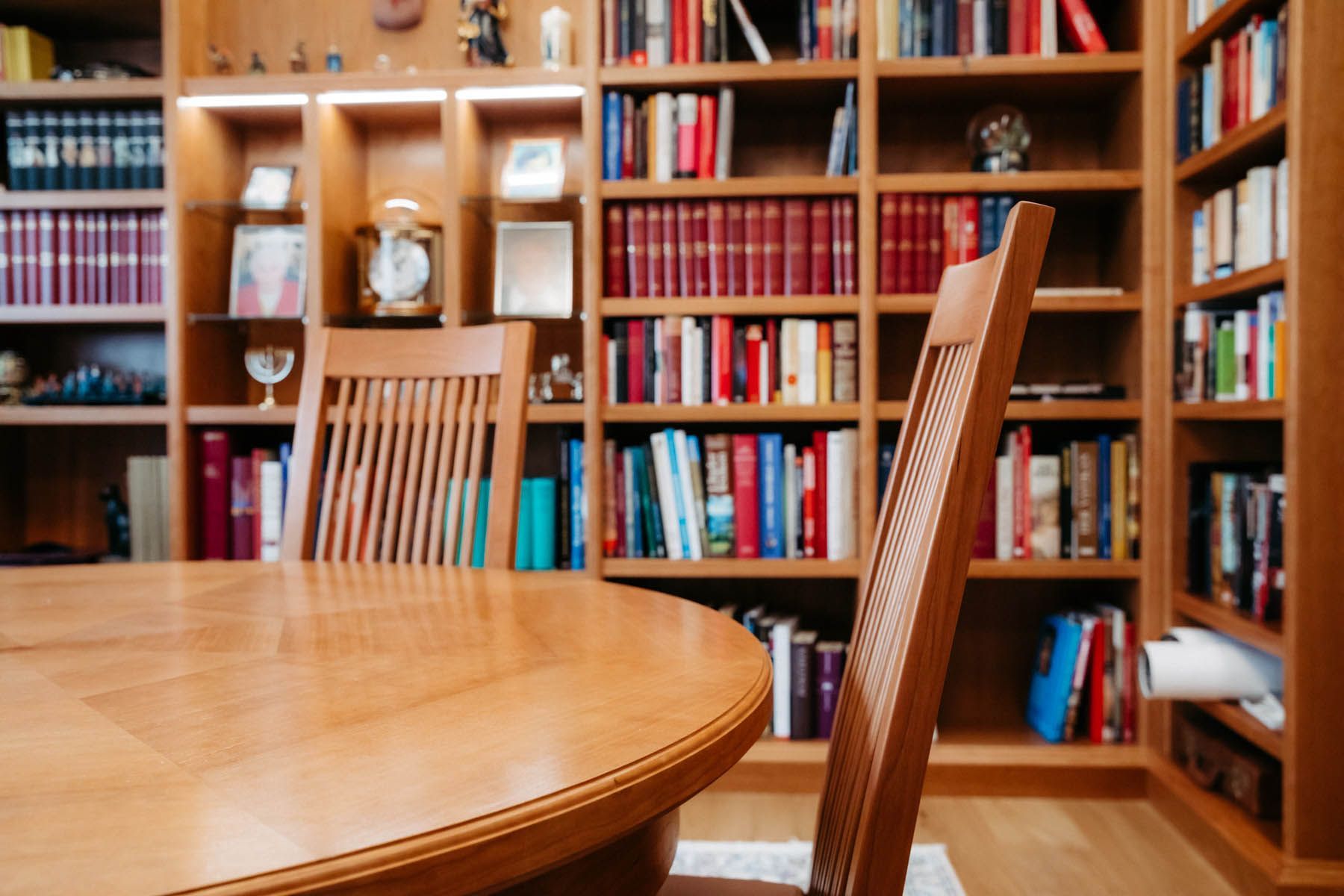 Holztisch und Stühle vor eingebauten Bücherregalen voller Bücher.