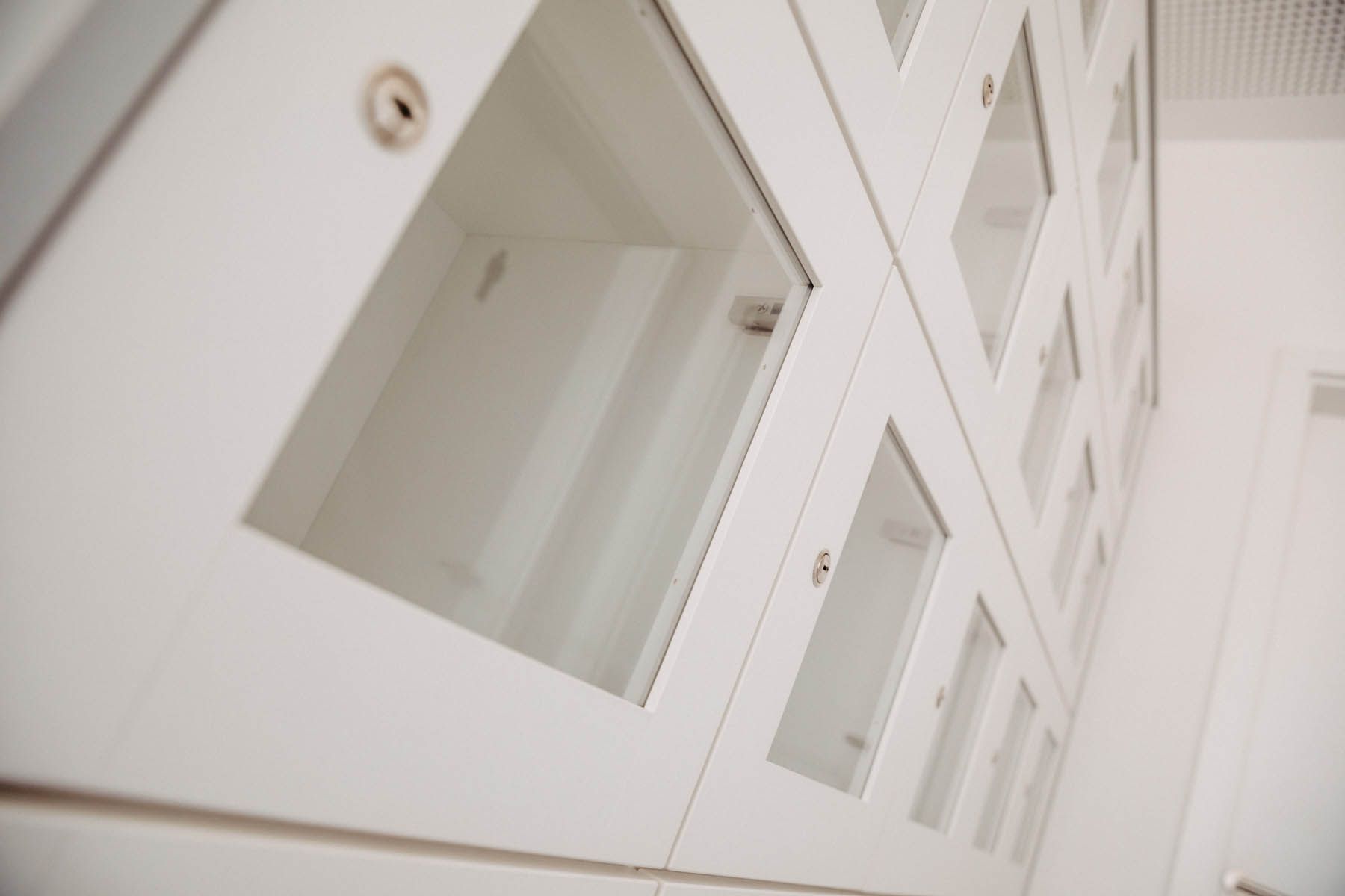 Weiße Schränke mit Glasfenstern, wahrscheinlich Lagerschränke, aus einem niedrigen Winkel betrachtet.